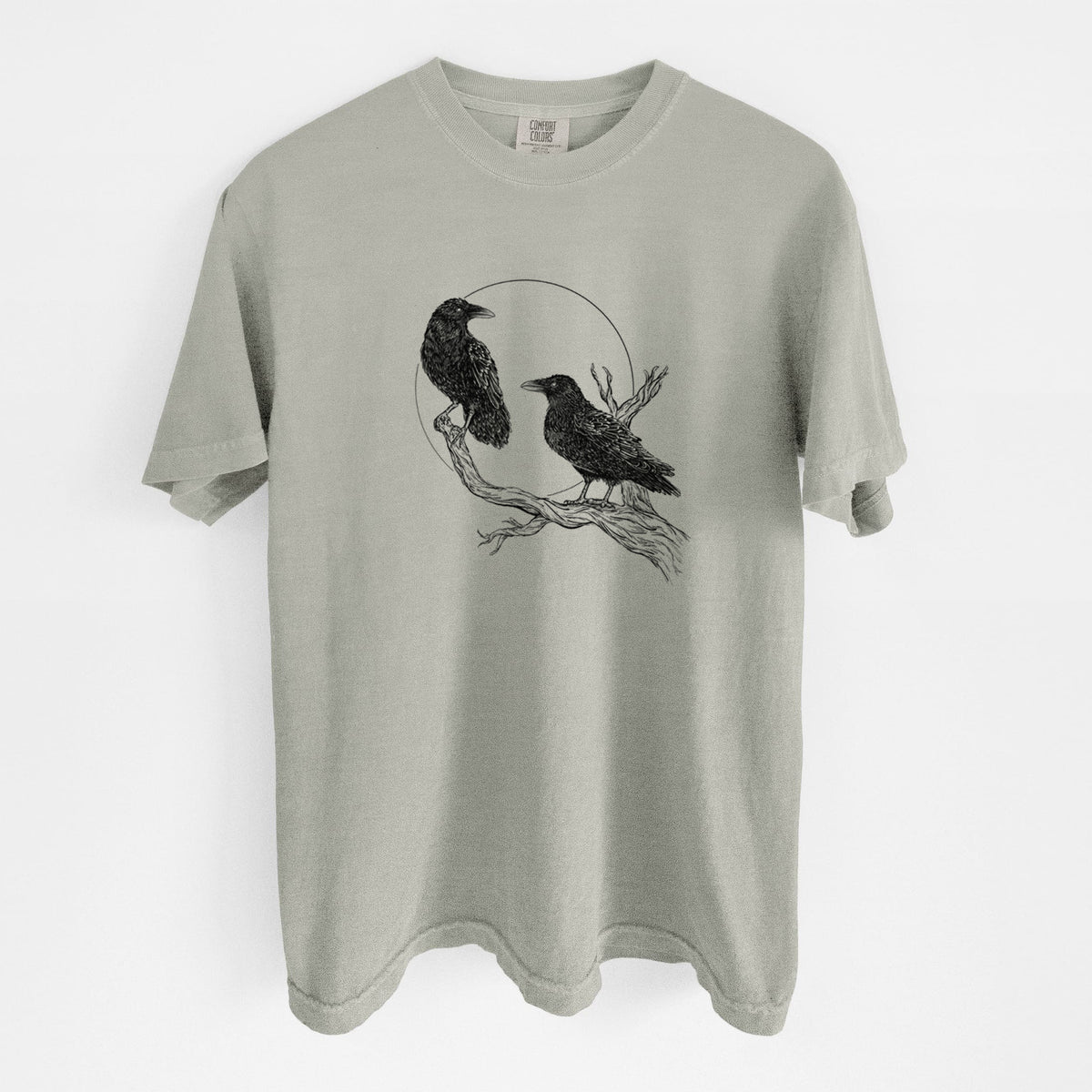 Sandstone beige Comfort Colors t-shirt laid flat, printed with a black ink illustration of two ravens perched on a branch in front of a full moon.