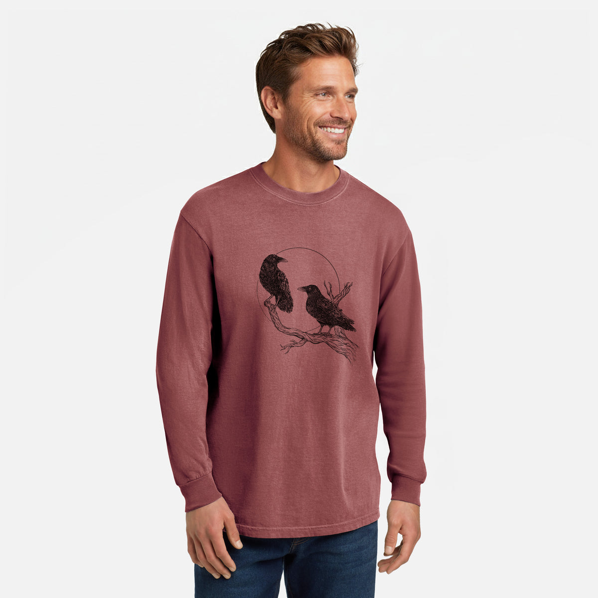 Brick red Comfort Colors long sleeve shirt printed with a black ink illustration of two ravens perched on a branch in front of a full moon, shown in a lifestyle photo.