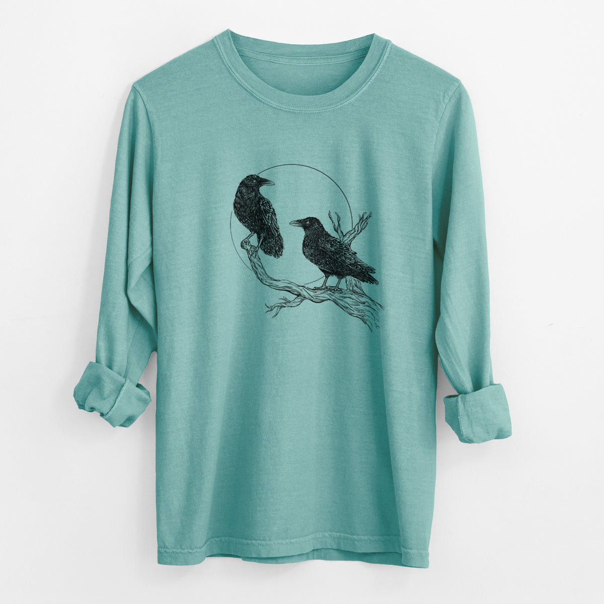 Reef green Comfort Colors long sleeve shirt laid flat with the cuffs rolled, printed with a black ink illustration of two ravens perched on a branch in front of a full moon.