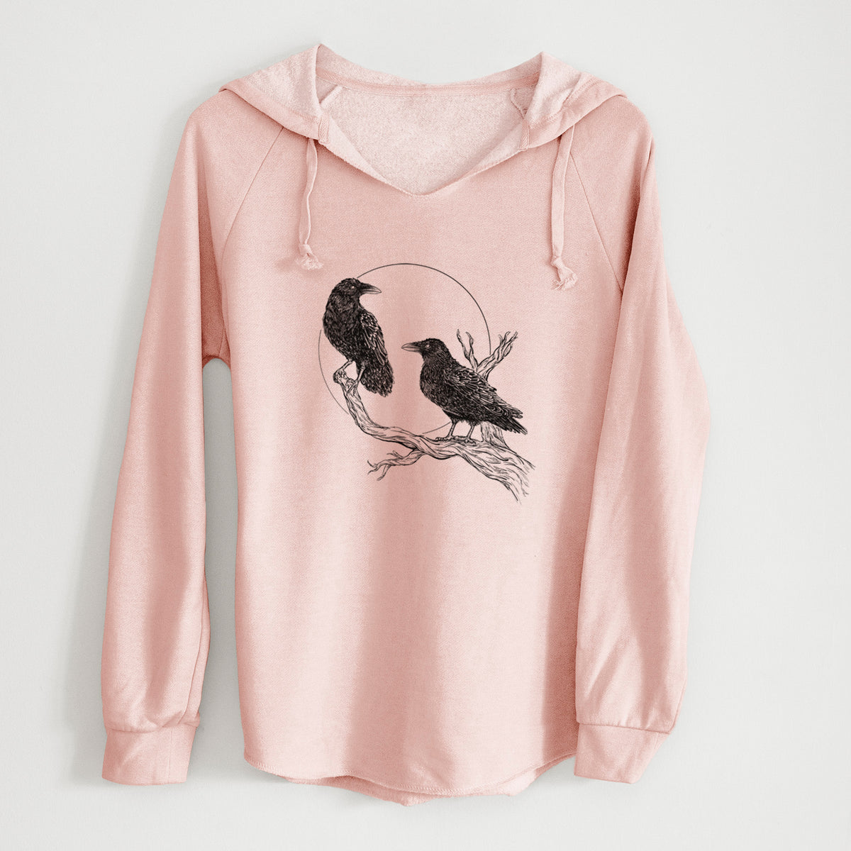 Blush pink women's Cali Wave hooded sweatshirt laid flat, printed with a black ink illustration of two ravens perched on a branch in front of a full moon.