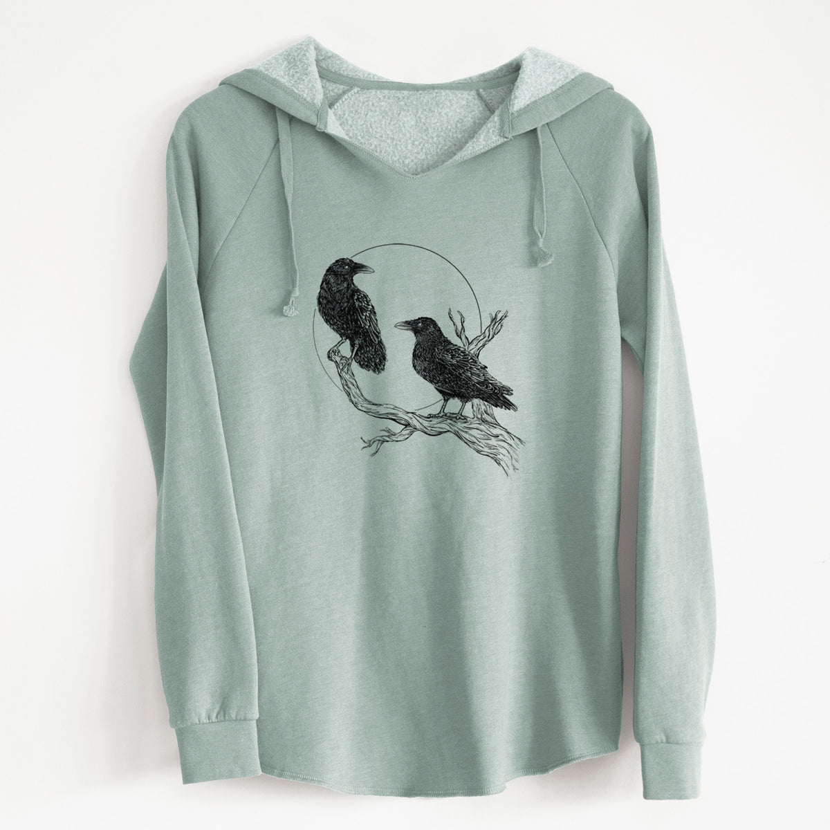 Sage green women's Cali Wave hooded sweatshirt laid flat, printed with a black ink illustration of two ravens perched on a branch in front of a full moon.