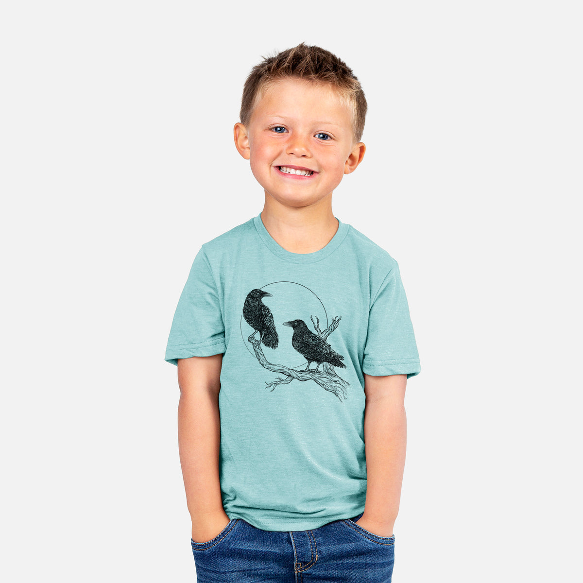 Smiling boy wearing a youth t-shirt printed with a black ink illustration of two ravens perched on a branch in front of a full moon.