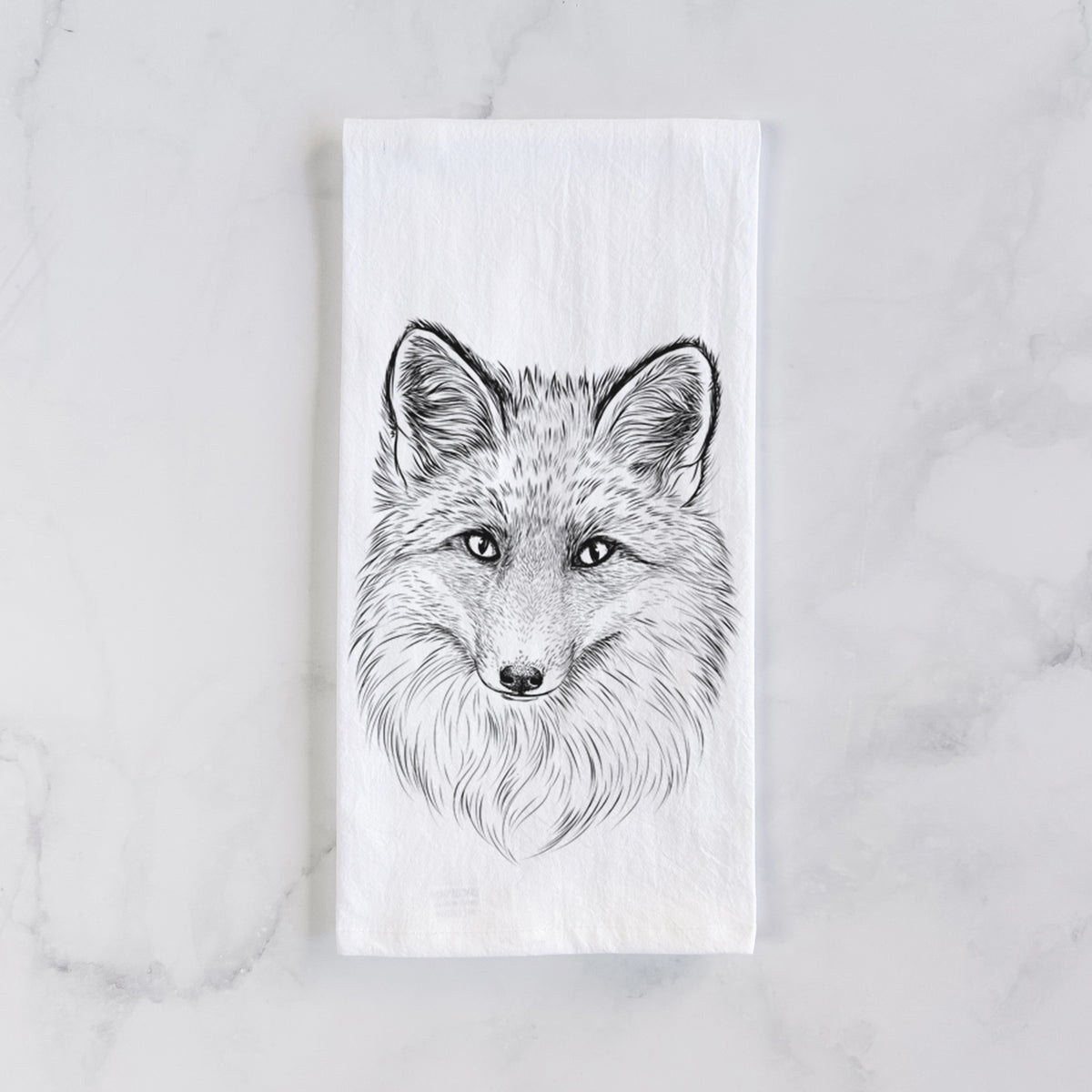White cotton tea towel laid flat on marble, printed with a detailed black ink sketch of a red fox's face looking straight ahead, its fur drawn in fine pencil-like strokes.
