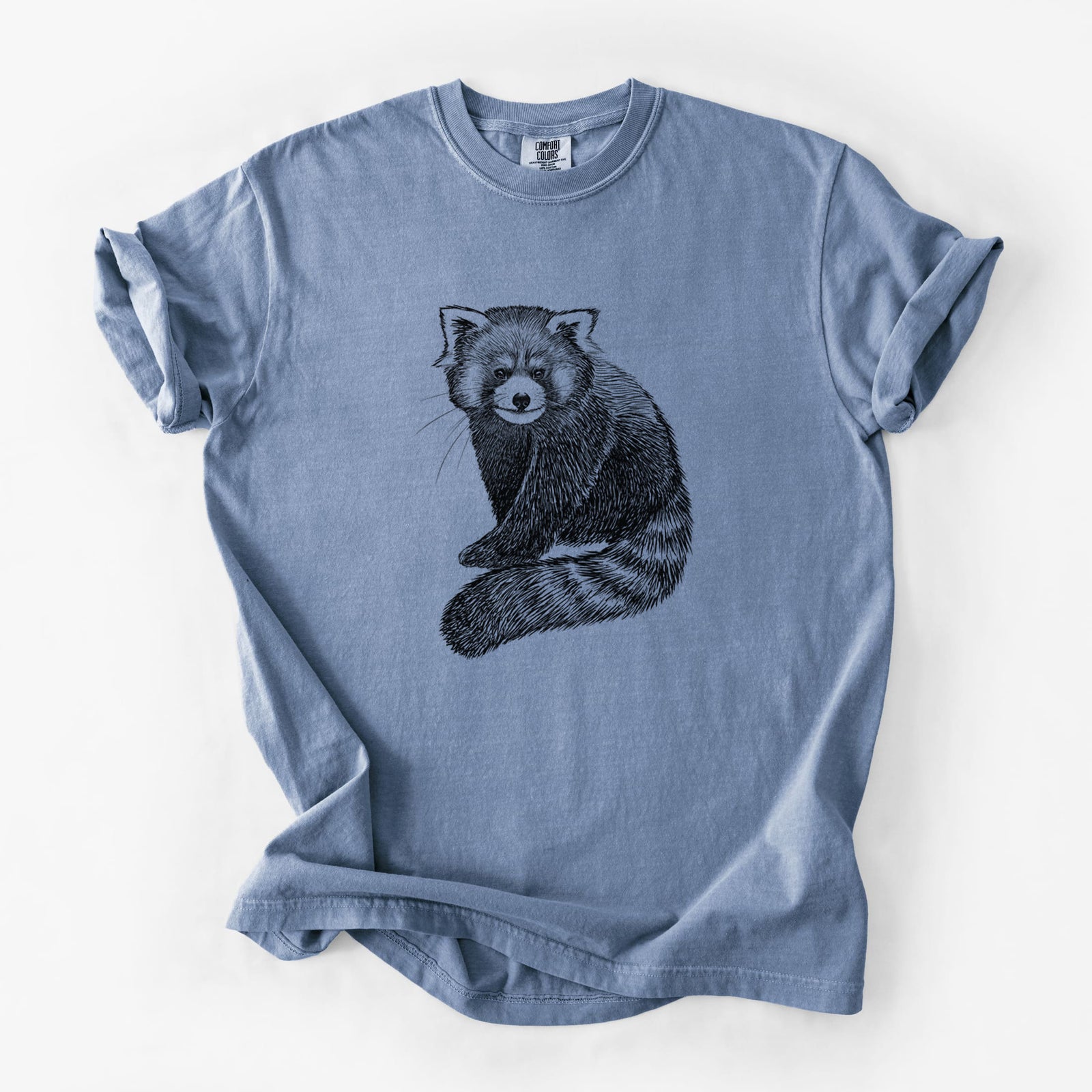 Blue jean Comfort Colors t-shirt laid flat, printed with a detailed black ink illustration of a red panda sitting with its striped tail wrapped around.