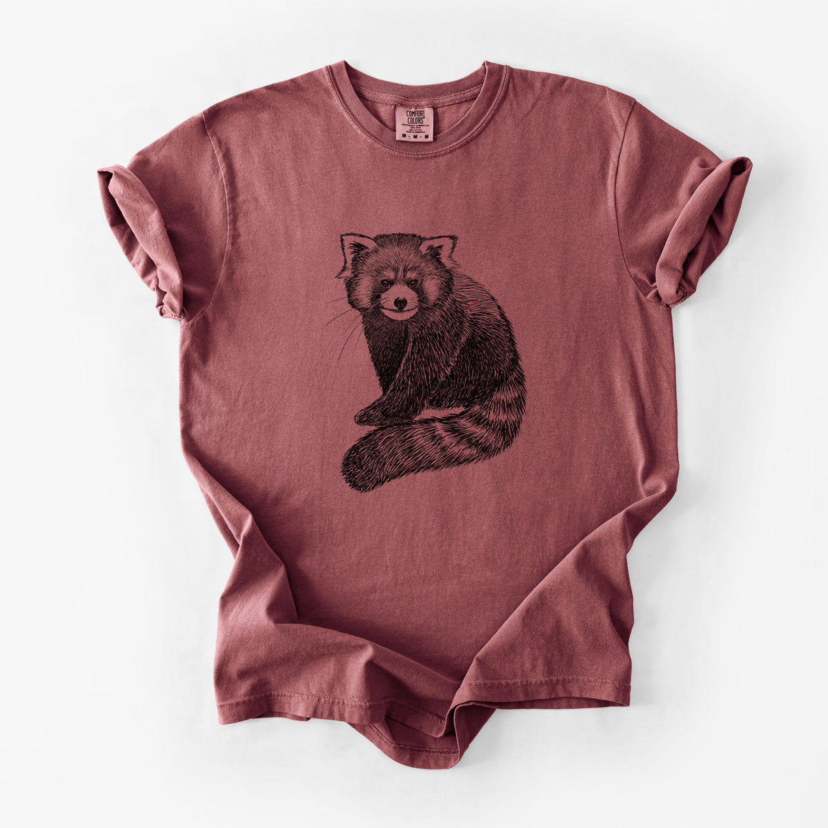 Brick red Comfort Colors t-shirt laid flat, printed with a detailed black ink illustration of a red panda sitting with its striped tail wrapped around.