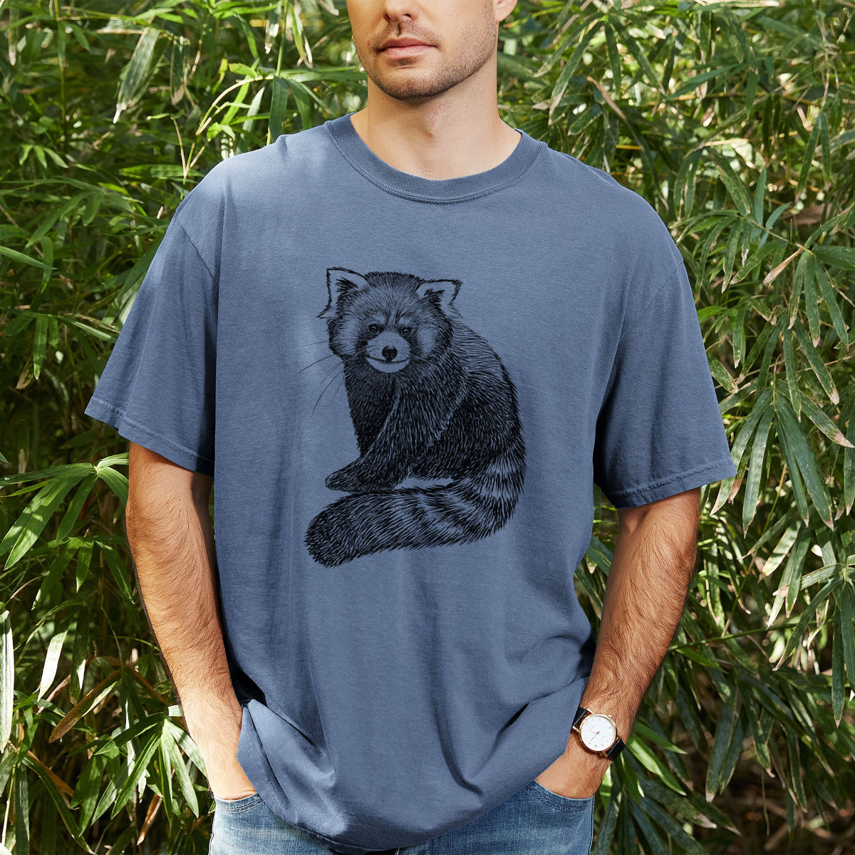Man wearing a Comfort Colors t-shirt printed with a detailed black ink illustration of a red panda sitting with its striped tail wrapped around, outdoors.