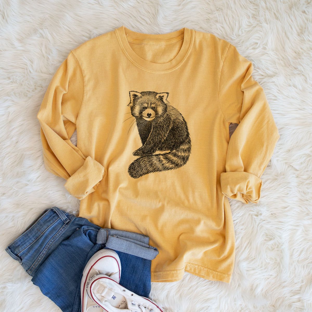 Golden wheat yellow Comfort Colors long sleeve shirt printed with a detailed black ink illustration of a red panda sitting with its striped tail wrapped around, shown in a lifestyle photo.