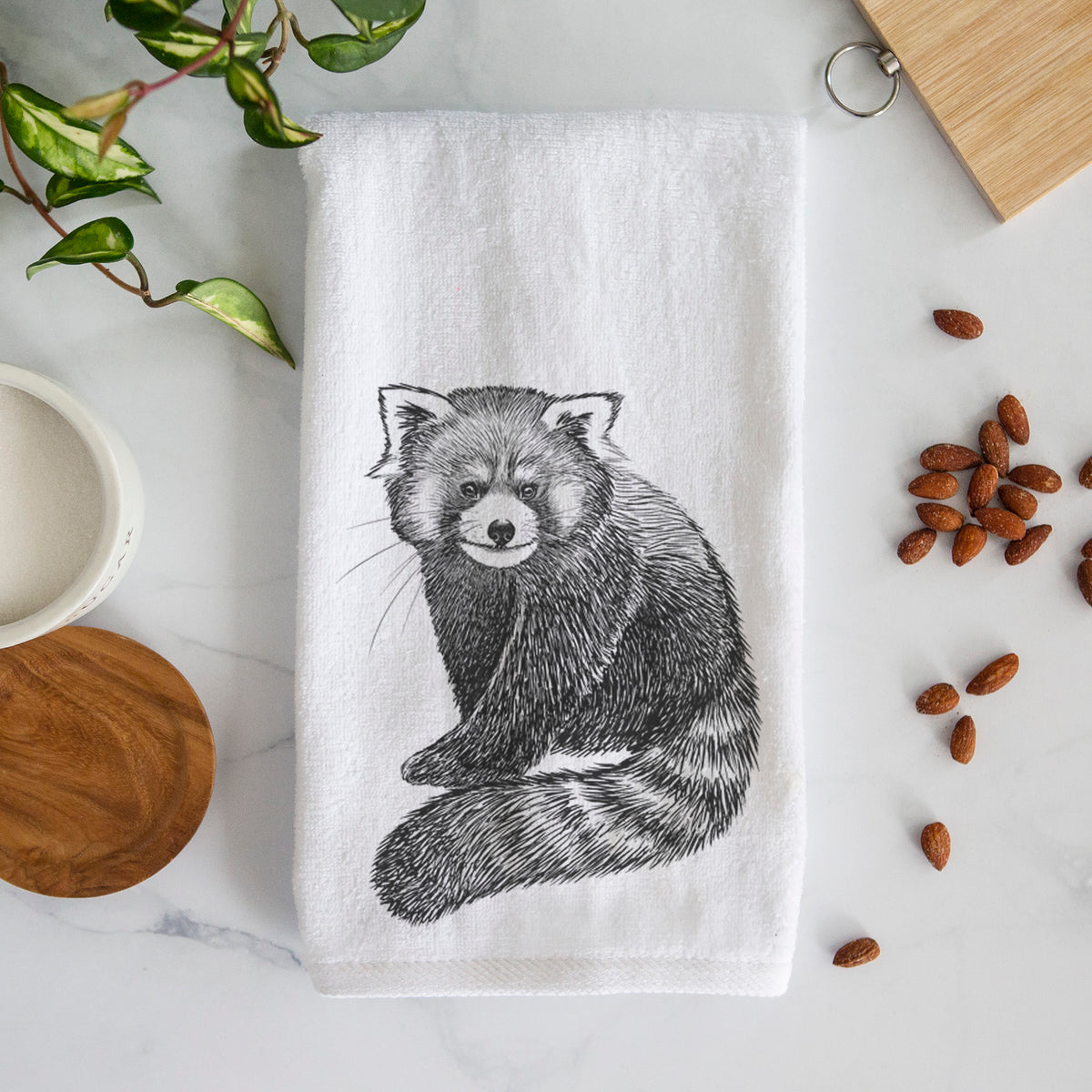 White hand towel printed with a detailed black ink illustration of a red panda sitting with its striped tail wrapped around.