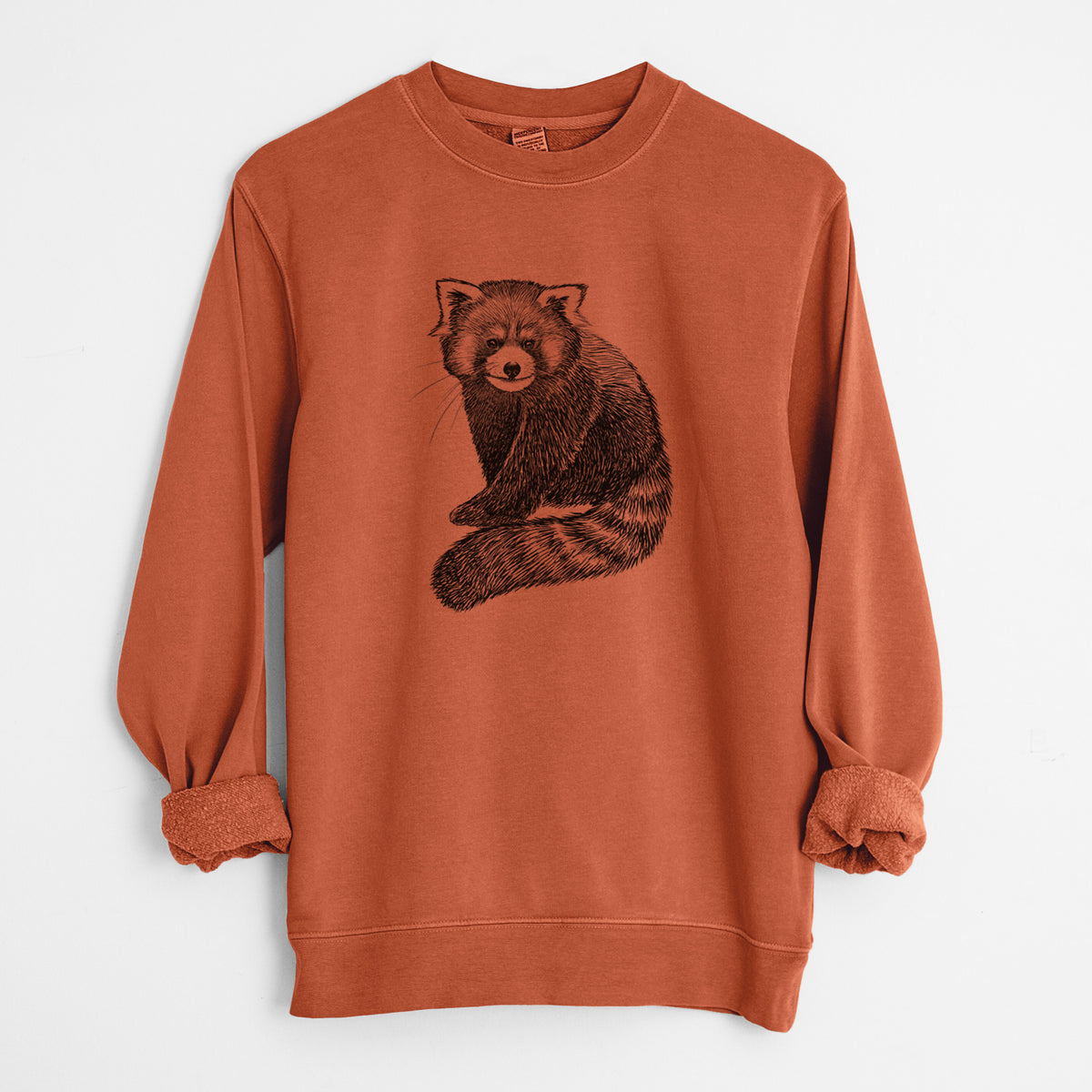 Amber orange pigment dyed crewneck sweatshirt laid flat with the sleeves rolled, printed with a detailed black ink illustration of a red panda sitting with its striped tail wrapped around.