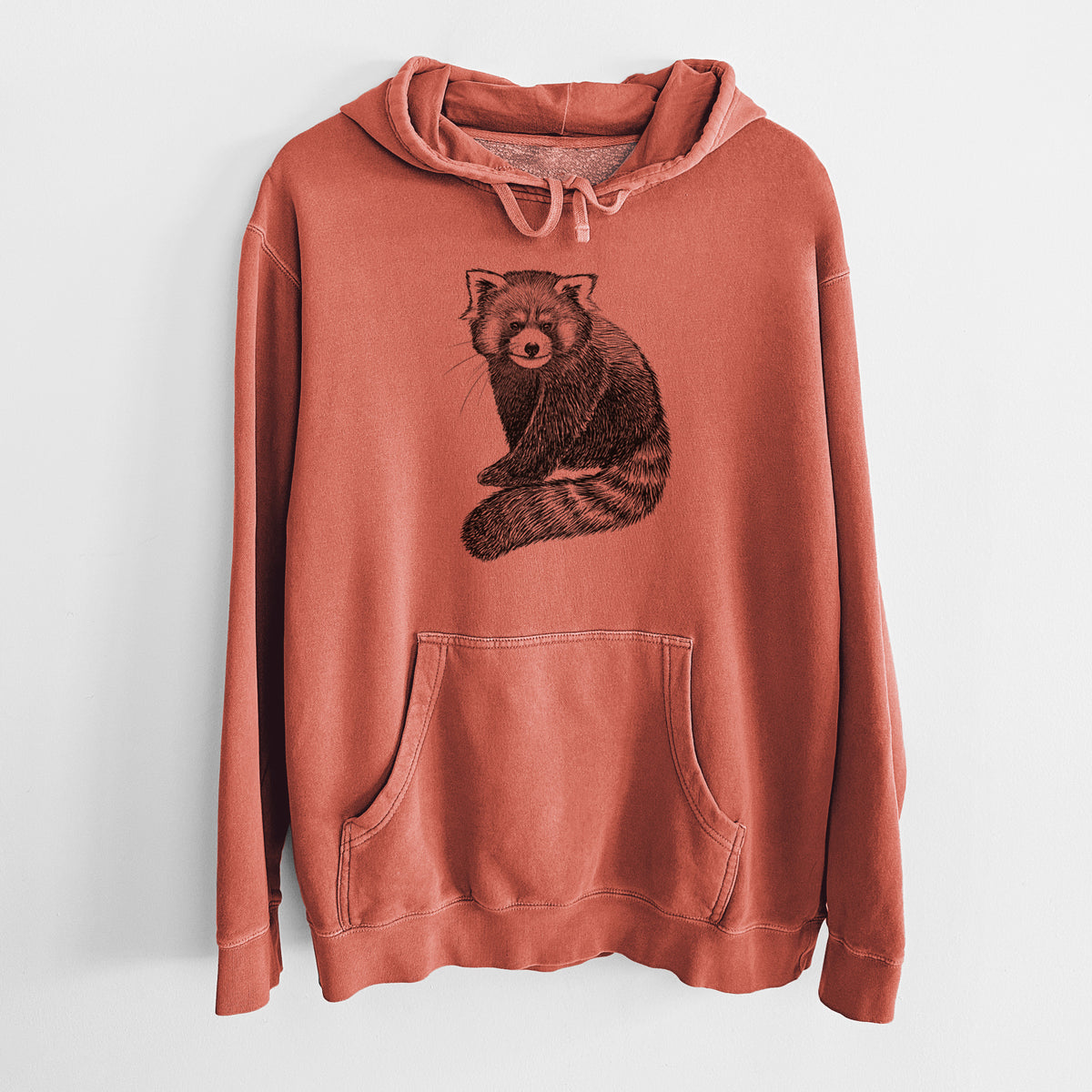 Amber orange pigment dyed hoodie laid flat, printed with a detailed black ink illustration of a red panda sitting with its striped tail wrapped around.
