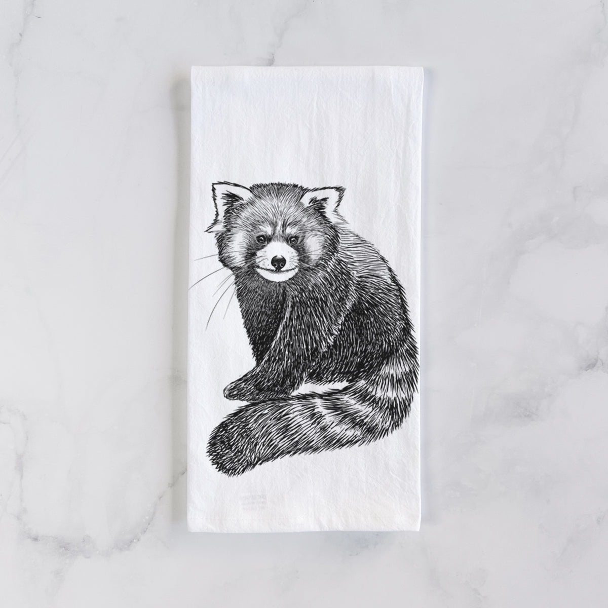 White cotton tea towel laid flat on marble, printed with a detailed black ink illustration of a red panda sitting with its striped tail wrapped around.
