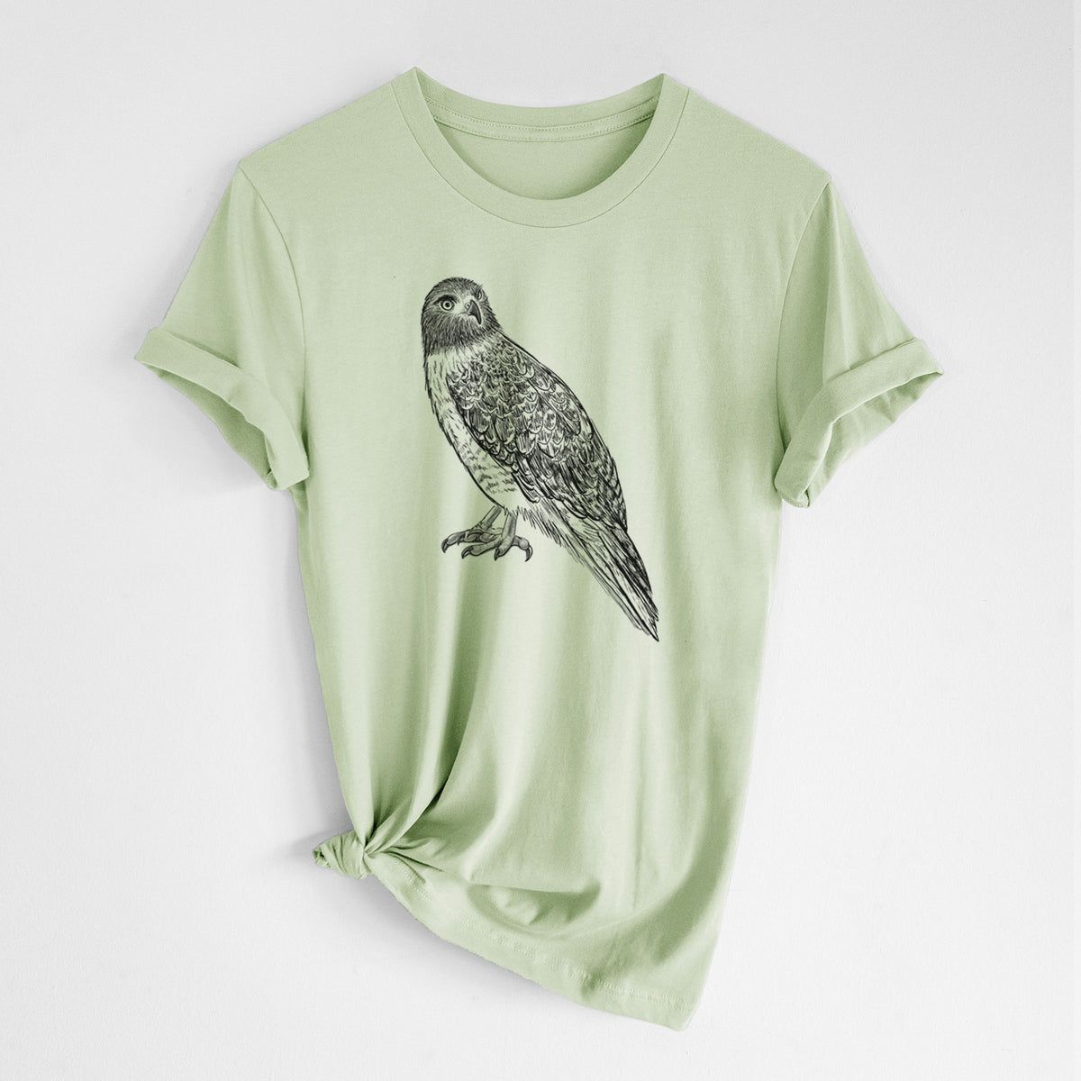 Spring green lightweight cotton t-shirt laid flat with the sleeves rolled, printed with a detailed black ink illustration of a red-tailed hawk perched.