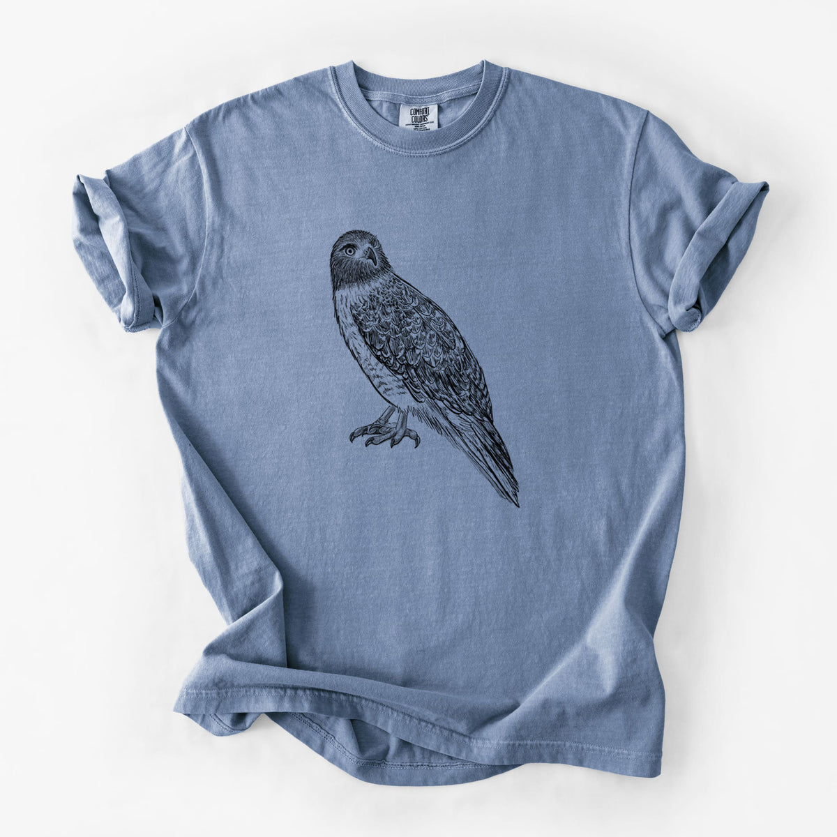 Blue jean Comfort Colors t-shirt laid flat, printed with a detailed black ink illustration of a red-tailed hawk perched.