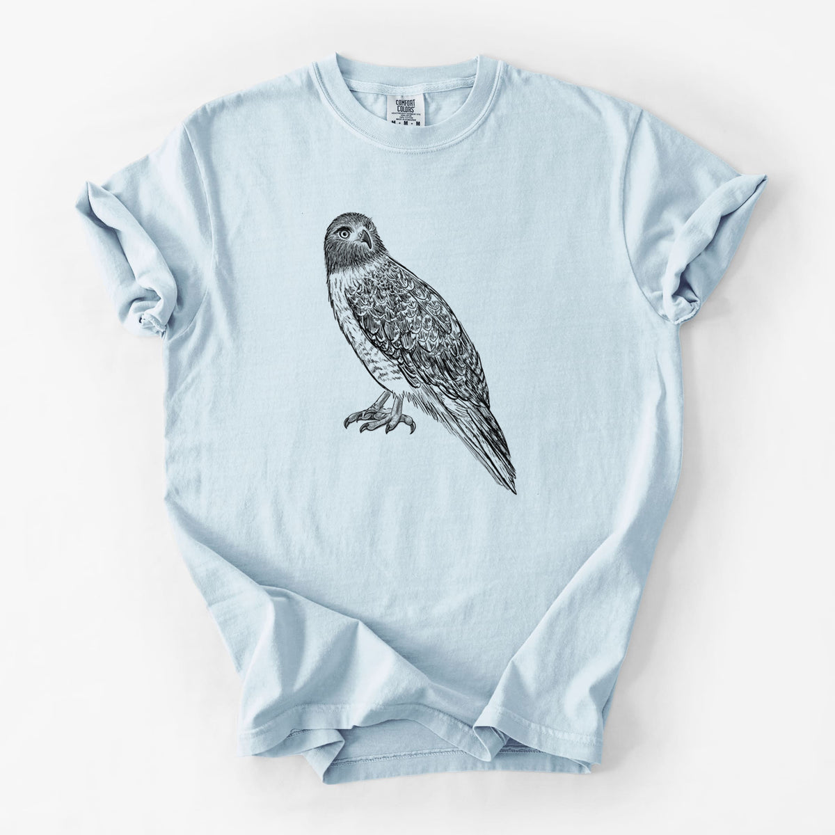 Chambray blue Comfort Colors t-shirt laid flat, printed with a detailed black ink illustration of a red-tailed hawk perched.