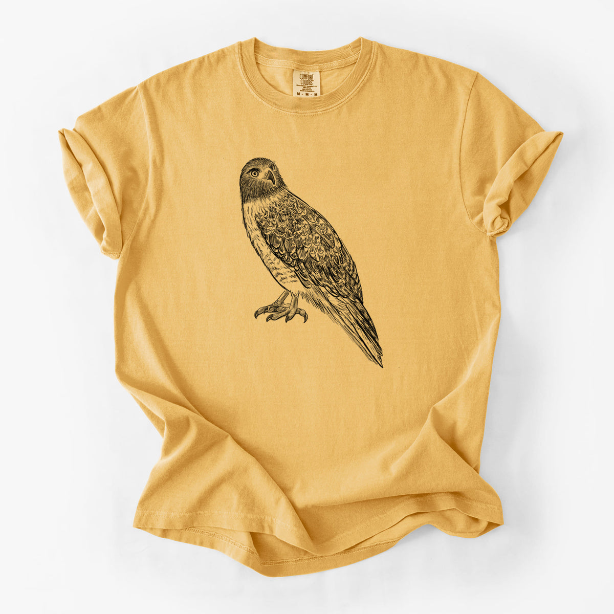 Golden wheat yellow Comfort Colors t-shirt laid flat, printed with a detailed black ink illustration of a red-tailed hawk perched.