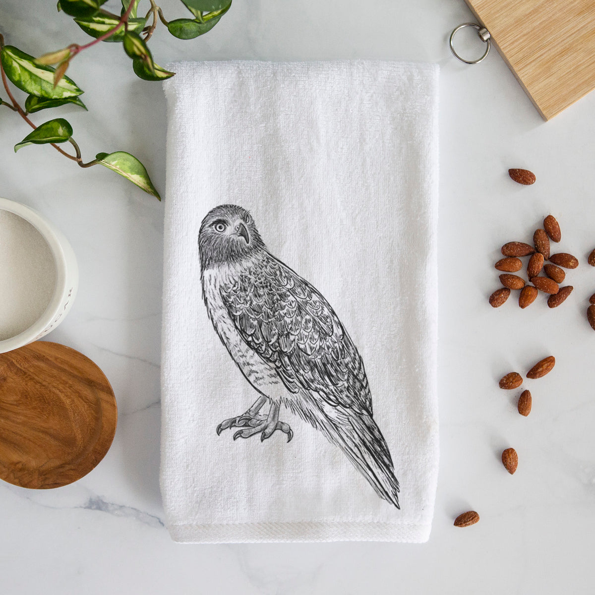 White hand towel printed with a detailed black ink illustration of a red-tailed hawk perched.