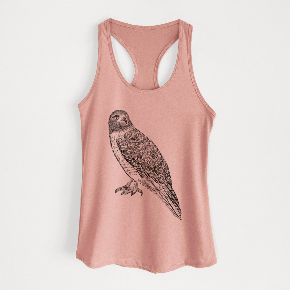 Desert pink women's racerback tank top laid flat, printed with a detailed black ink illustration of a red-tailed hawk perched.