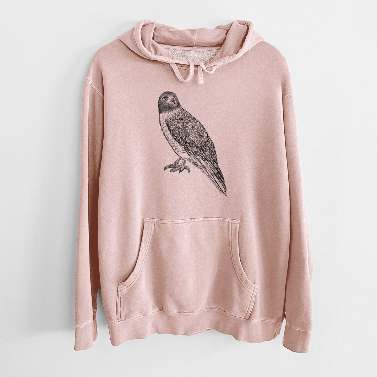 Dusty pink pigment dyed hoodie laid flat, printed with a detailed black ink illustration of a red-tailed hawk perched.