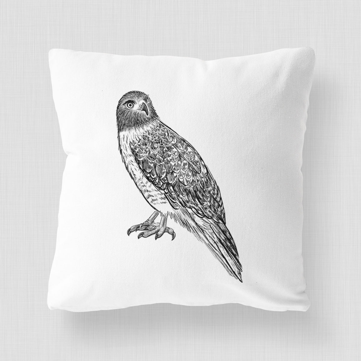 White pillow cover printed with a detailed black ink illustration of a red-tailed hawk perched.