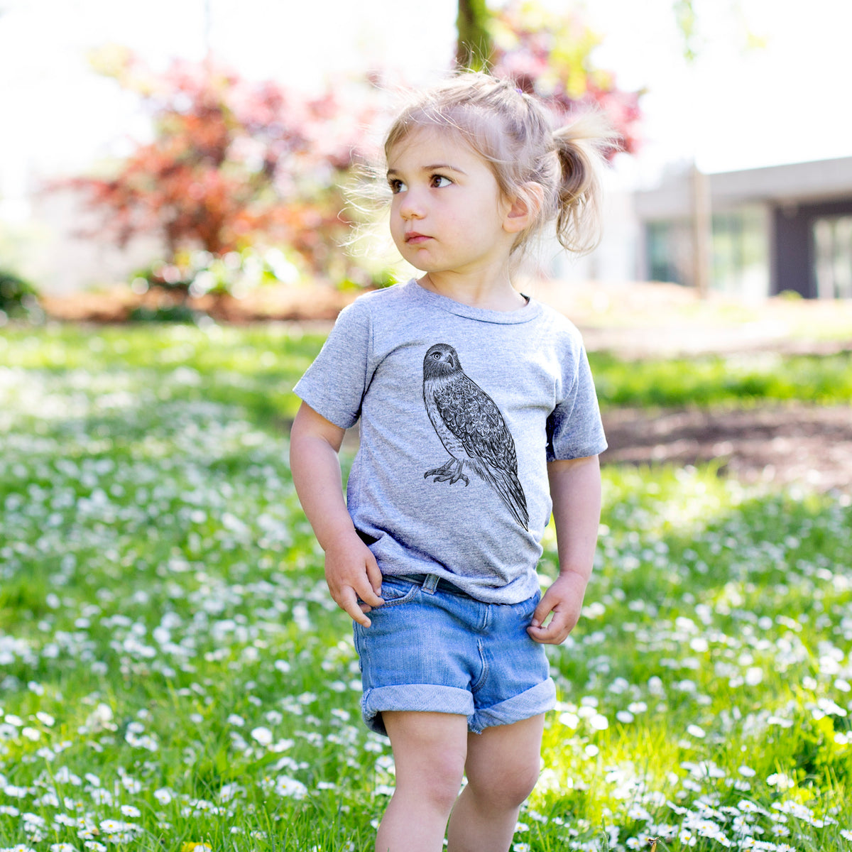 Toddler girl walking outdoors wearing a t-shirt printed with a detailed black ink illustration of a red-tailed hawk perched.