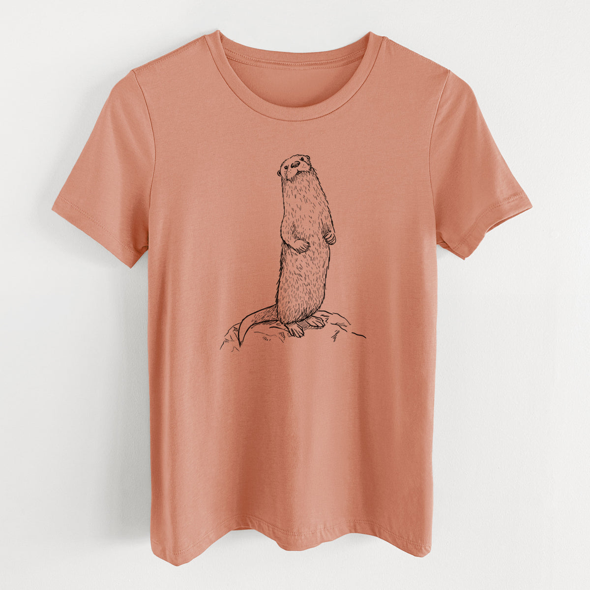 Terracotta orange women's relaxed fit cotton t-shirt laid flat, printed with a black ink illustration of a river otter standing upright on a rock.