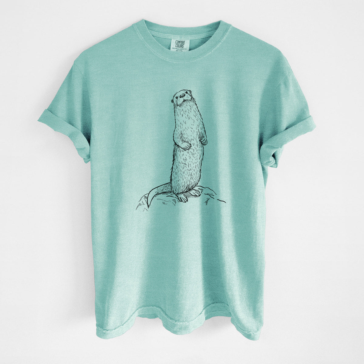 Chalky mint Comfort Colors t-shirt laid flat, printed with a black ink illustration of a river otter standing upright on a rock.