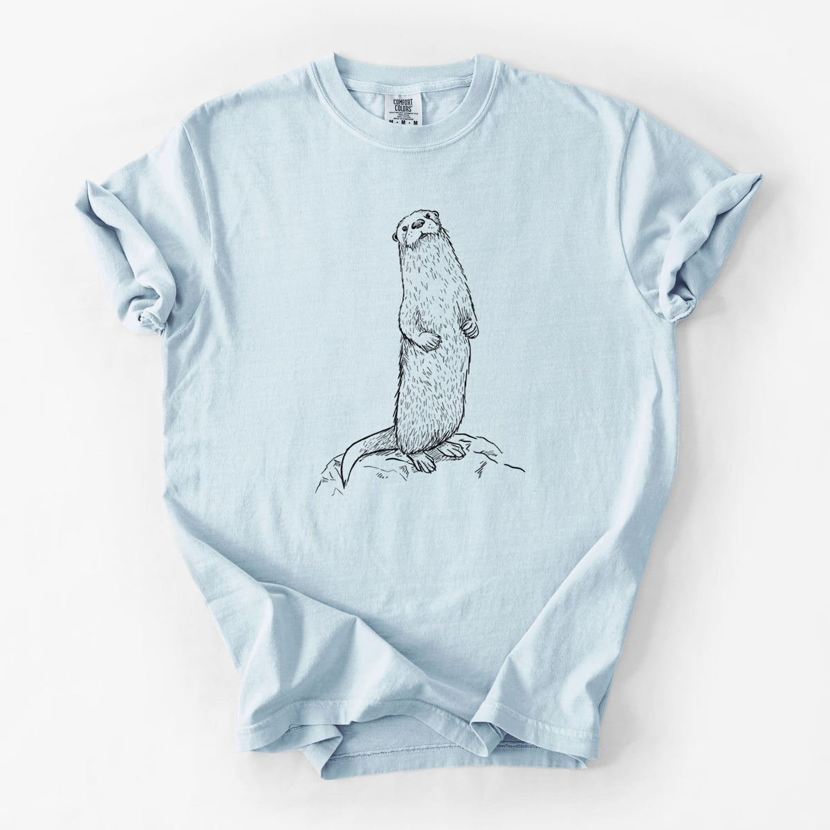 Chambray blue Comfort Colors t-shirt laid flat, printed with a black ink illustration of a river otter standing upright on a rock.