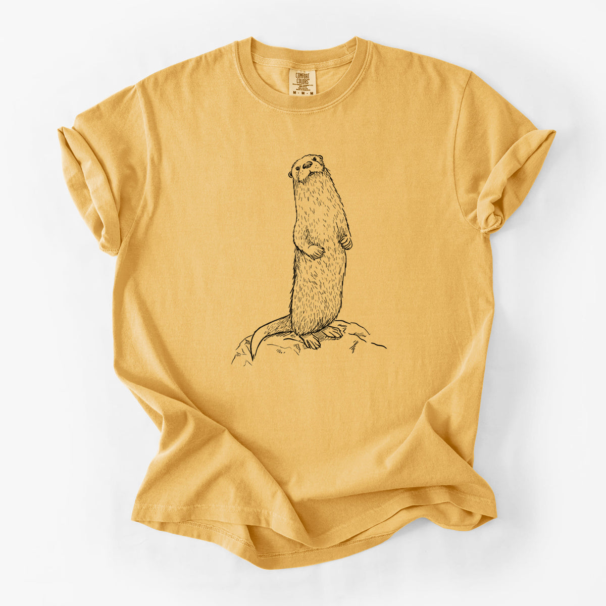 Golden wheat yellow Comfort Colors t-shirt laid flat, printed with a black ink illustration of a river otter standing upright on a rock.