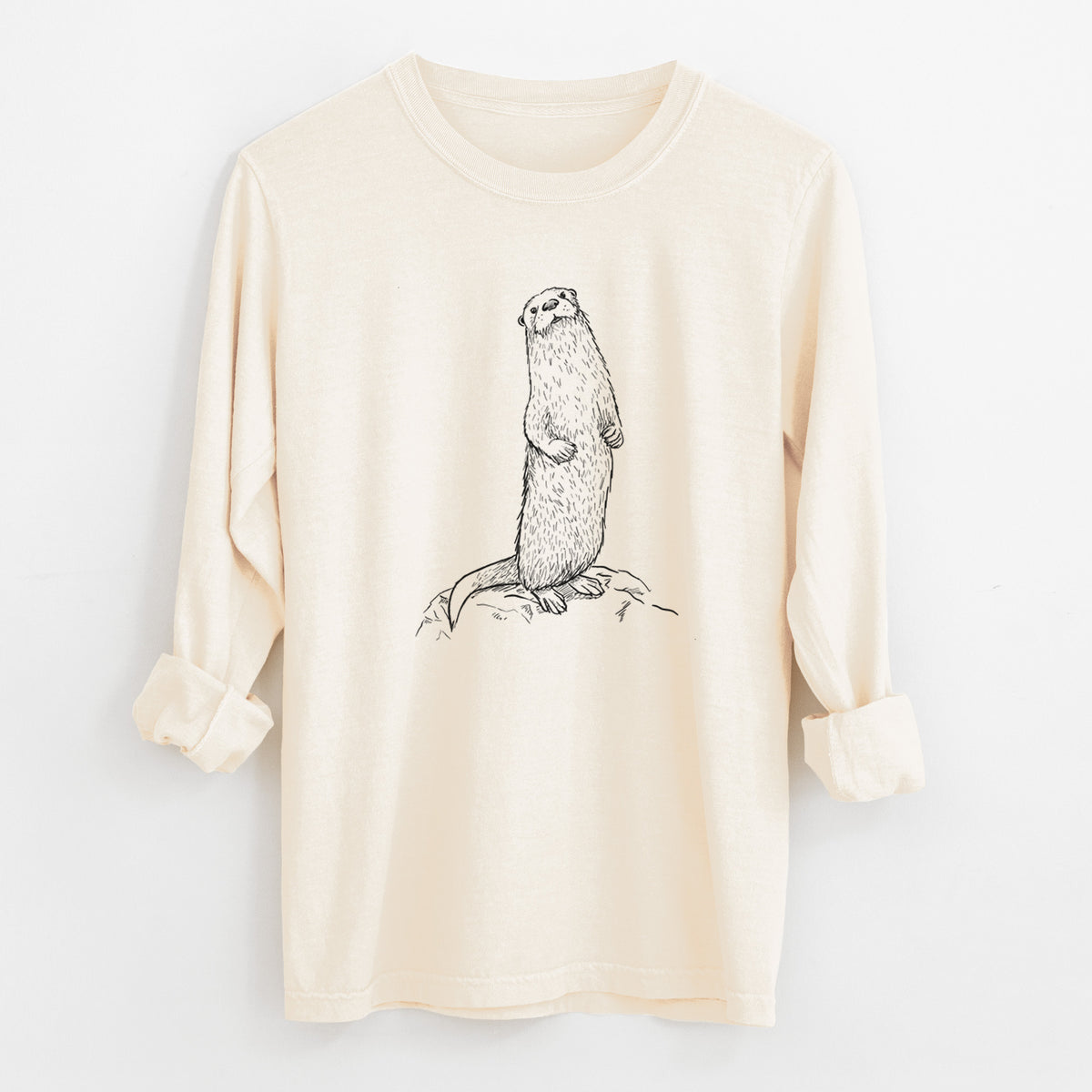 Ivory Comfort Colors long sleeve shirt laid flat with the cuffs rolled, printed with a black ink illustration of a river otter standing upright on a rock.
