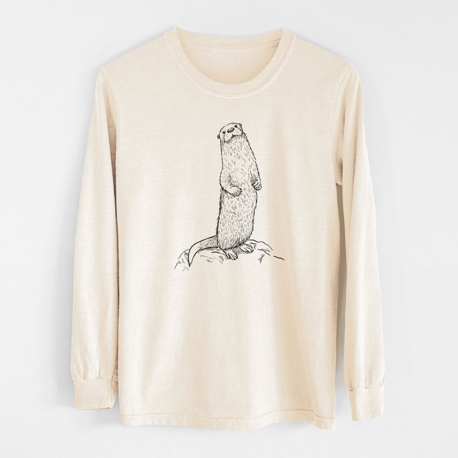 Ivory Comfort Colors long sleeve shirt laid flat, printed with a black ink illustration of a river otter standing upright on a rock.