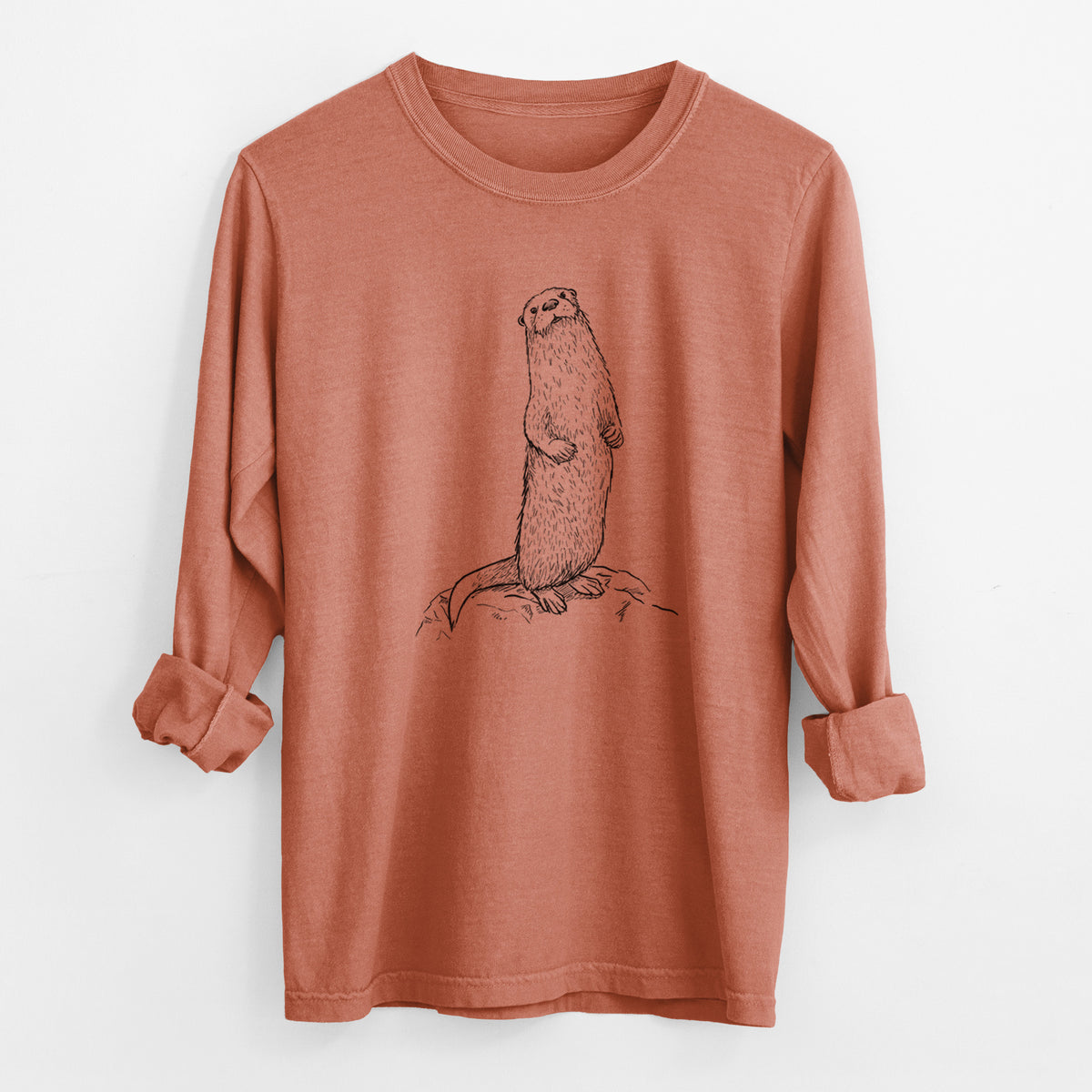 Yam burnt orange Comfort Colors long sleeve shirt laid flat with the cuffs rolled, printed with a black ink illustration of a river otter standing upright on a rock.