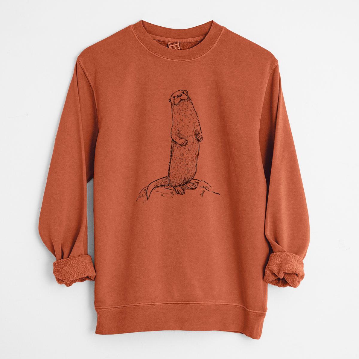 Amber orange pigment dyed crewneck sweatshirt laid flat with the sleeves rolled, printed with a black ink illustration of a river otter standing upright on a rock.