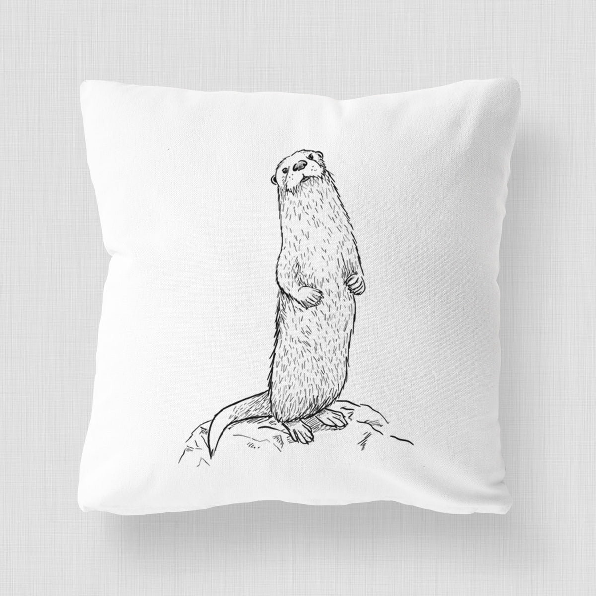 White pillow cover printed with a black ink illustration of a river otter standing upright on a rock.