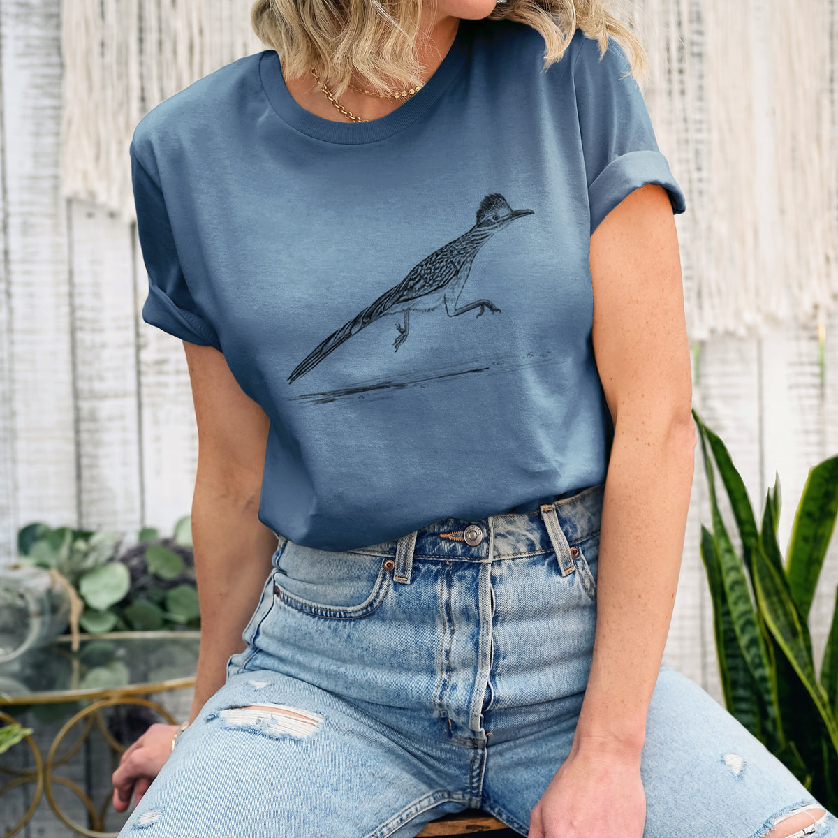 Woman wearing a steel blue lightweight cotton t-shirt printed with a black ink illustration of a roadrunner running.