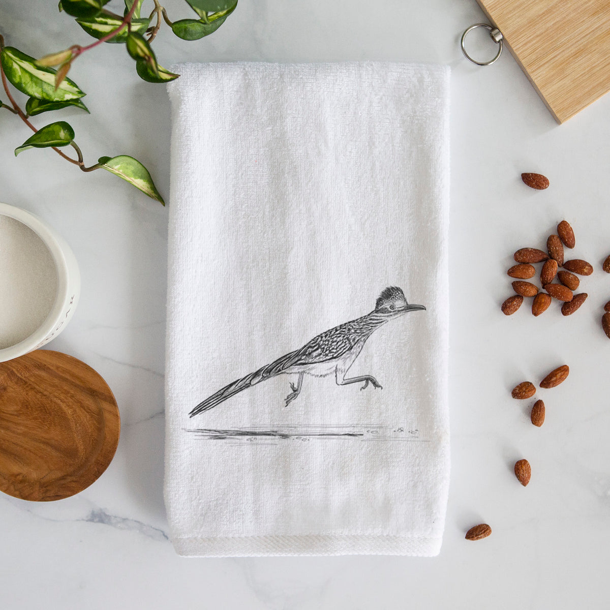 White hand towel printed with a black ink illustration of a roadrunner running.