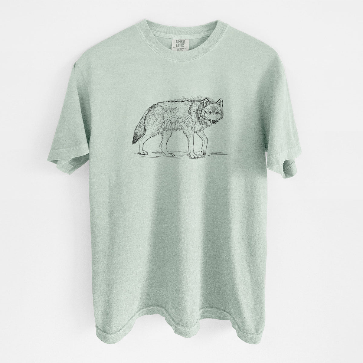 Bay green Comfort Colors t-shirt laid flat, printed with a detailed black ink illustration of a grey wolf walking.