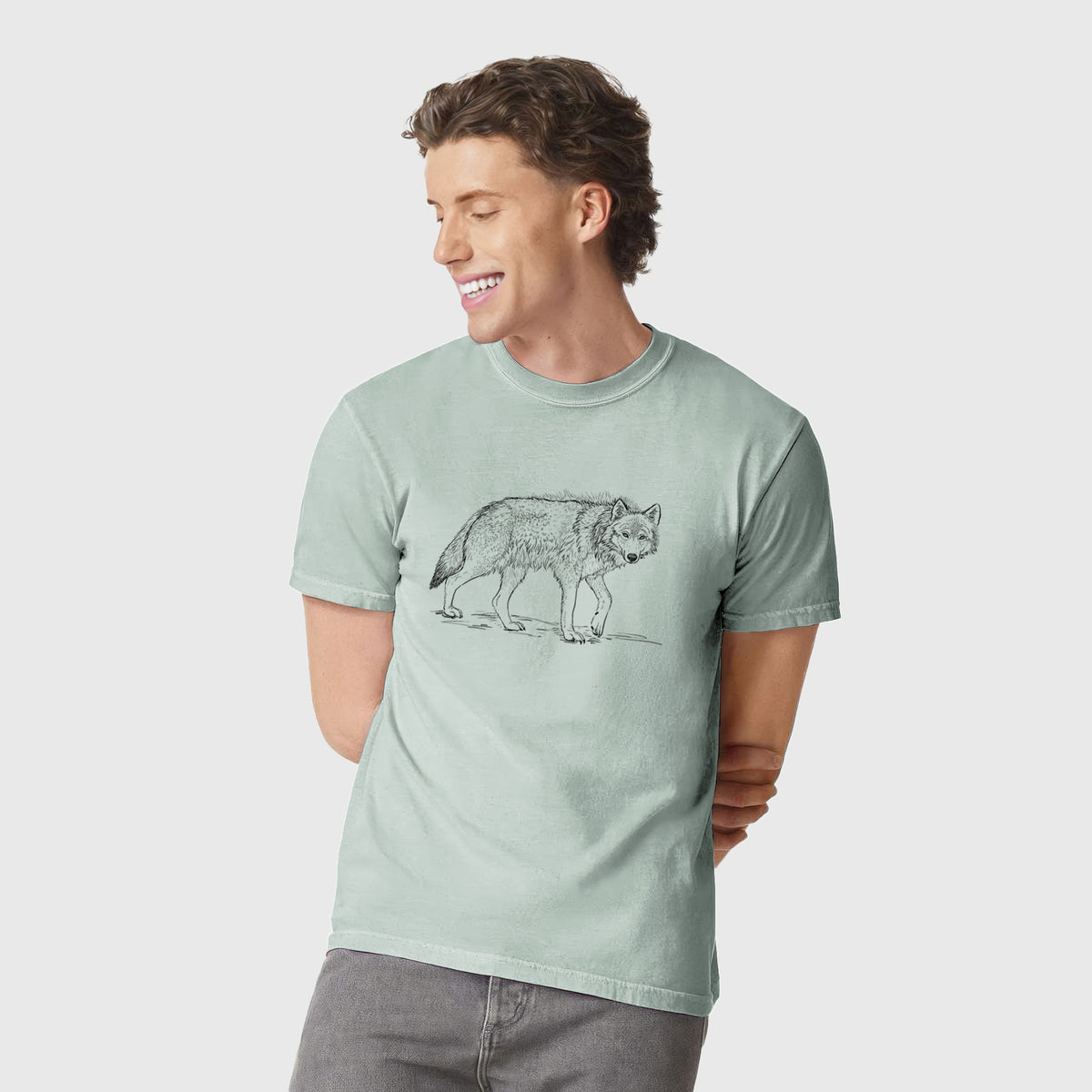 Man wearing a Comfort Colors t-shirt printed with a detailed black ink illustration of a grey wolf walking.