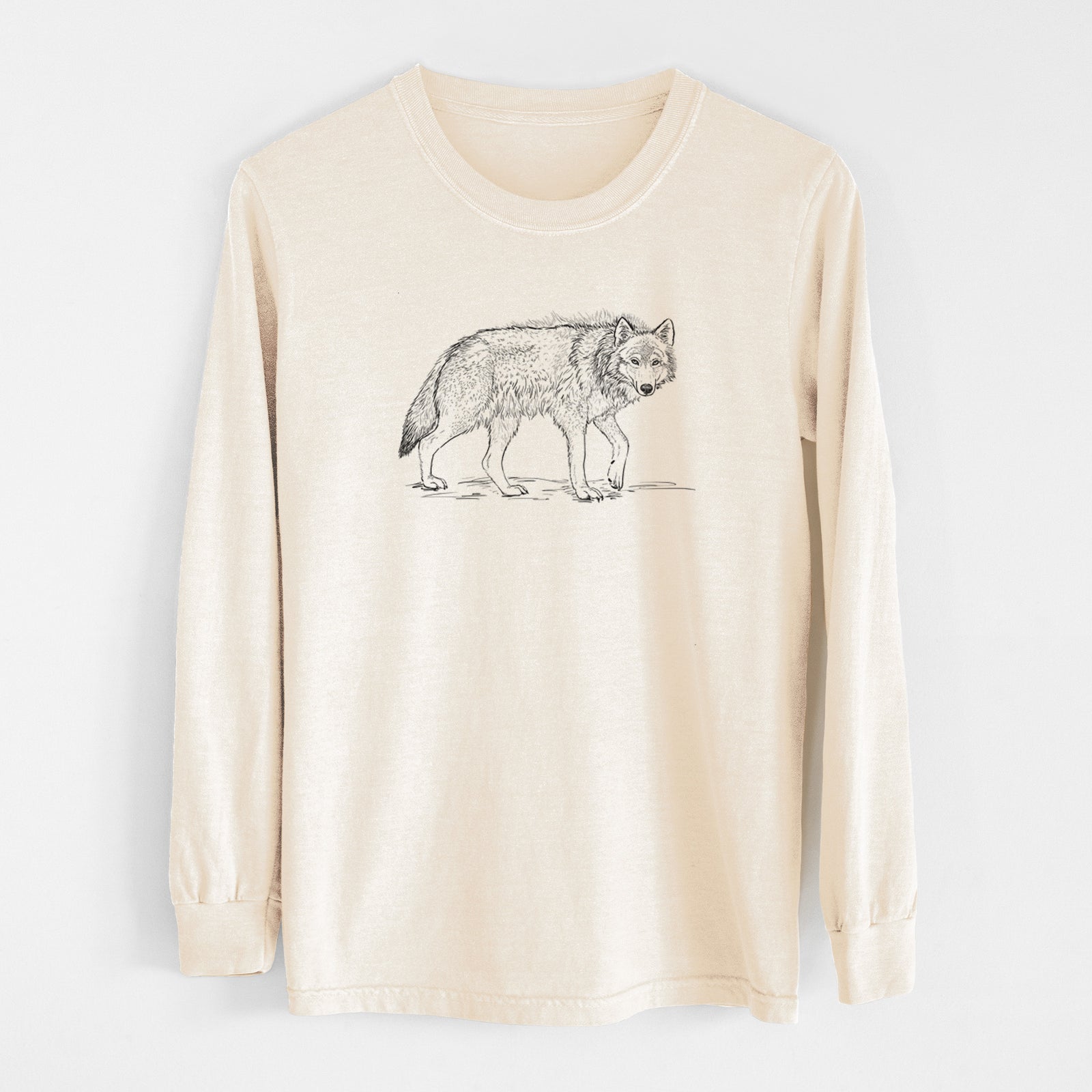 Ivory Comfort Colors long sleeve shirt laid flat, printed with a detailed black ink illustration of a grey wolf walking.