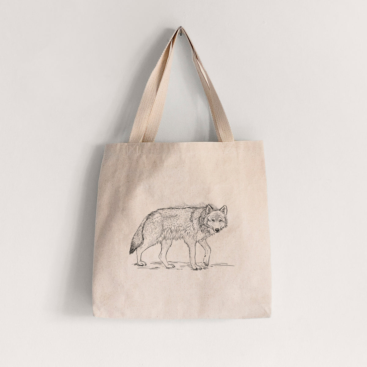 Natural canvas tote bag printed with a detailed black ink illustration of a grey wolf walking.
