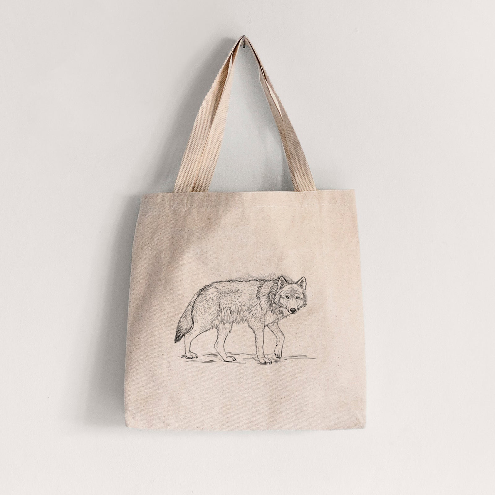 Natural canvas tote bag printed with a detailed black ink illustration of a grey wolf walking.