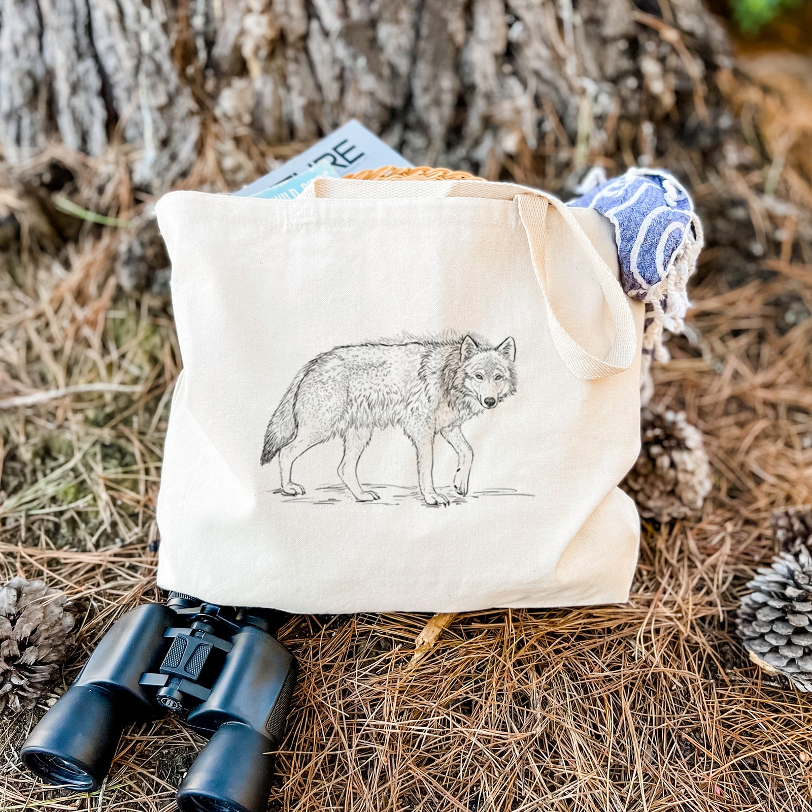 Natural canvas tote bag printed with a detailed black ink illustration of a grey wolf walking.