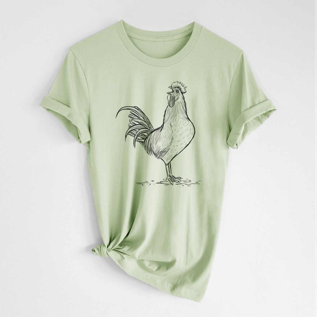 Spring green lightweight cotton t-shirt laid flat with the sleeves rolled, printed with a detailed black ink illustration of a rooster crowing.
