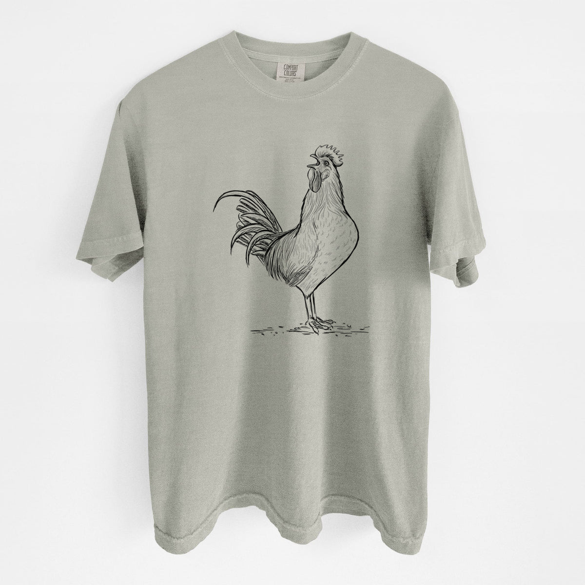 Sandstone beige Comfort Colors t-shirt laid flat, printed with a detailed black ink illustration of a rooster crowing.