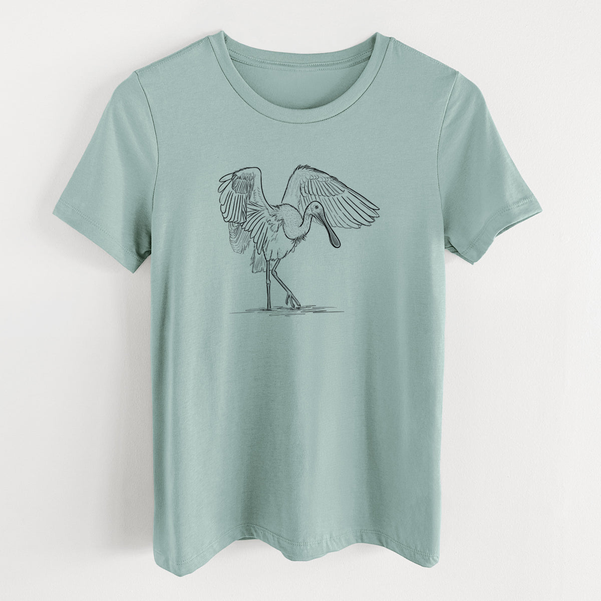 Dusty blue women's relaxed fit cotton t-shirt laid flat, printed with a black ink illustration of a roseate spoonbill standing with its wings spread.
