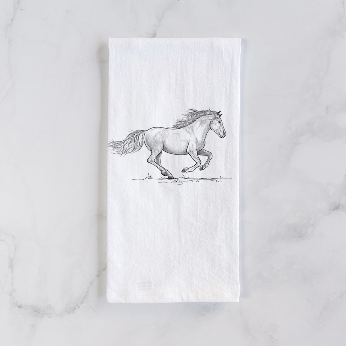 White cotton tea towel laid flat on marble, printed with a black ink illustration of a mustang horse running.