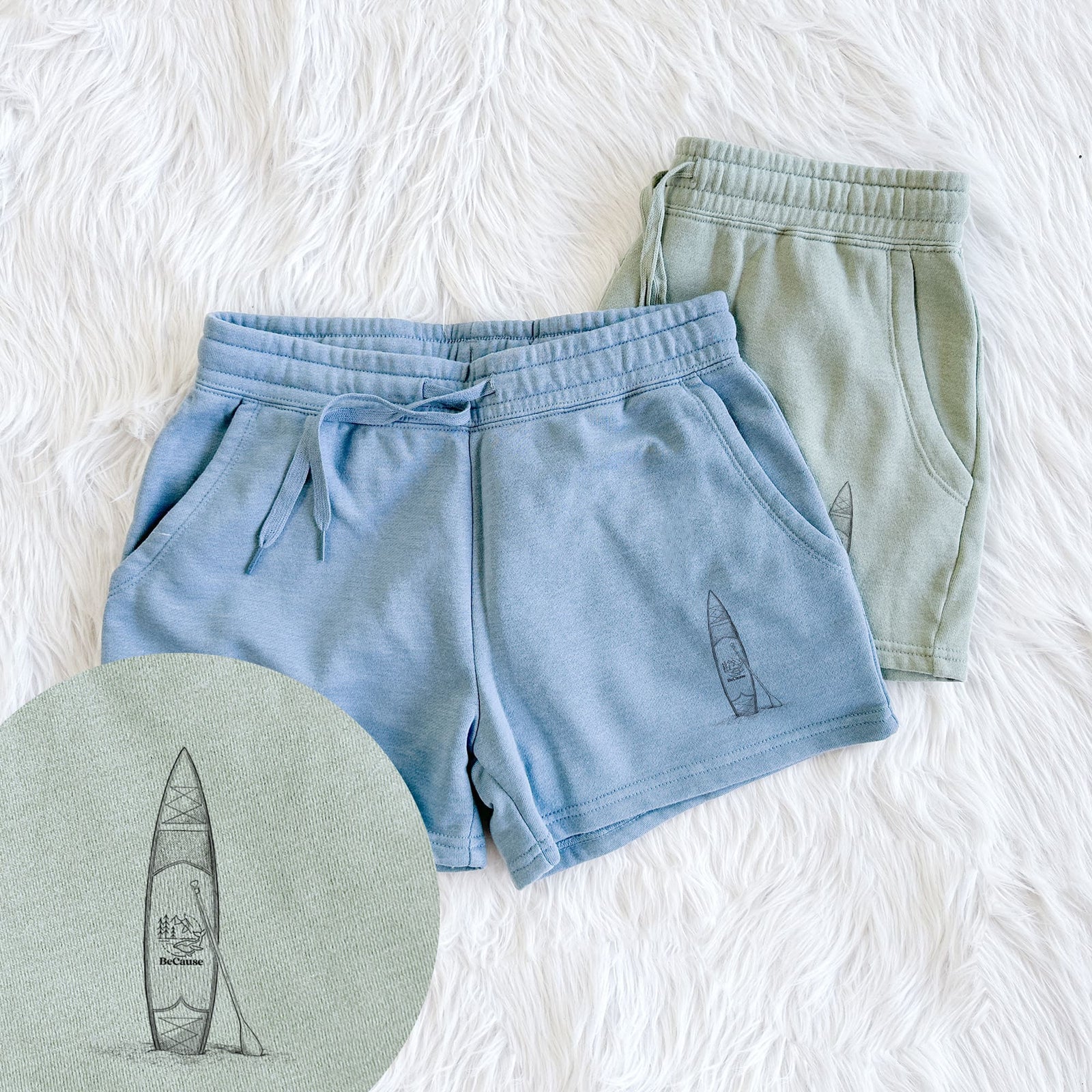 Two pairs of Cali Wave shorts in different colors printed with a black ink illustration of a stand-up paddleboard with a paddle, with a close-up of the print.