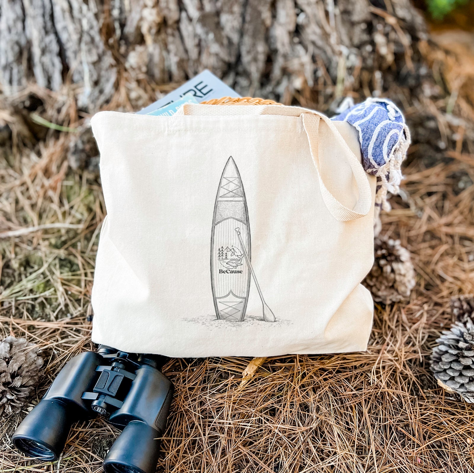 Natural canvas tote bag printed with a black ink illustration of a stand-up paddleboard with a paddle.