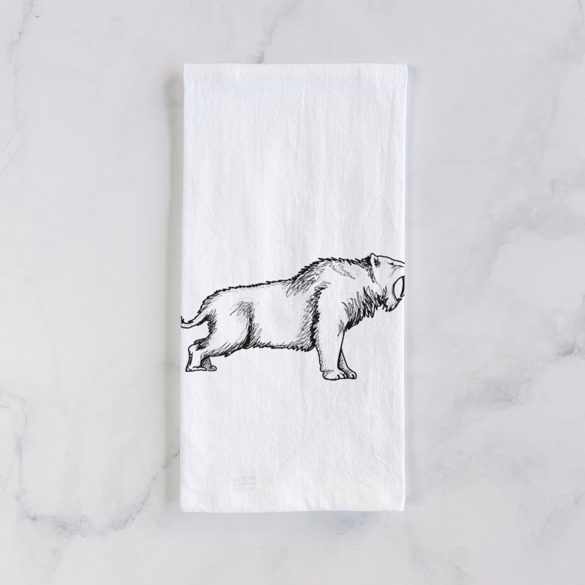 White cotton tea towel laid flat on marble, printed with a black ink illustration of a saber-toothed tiger walking.