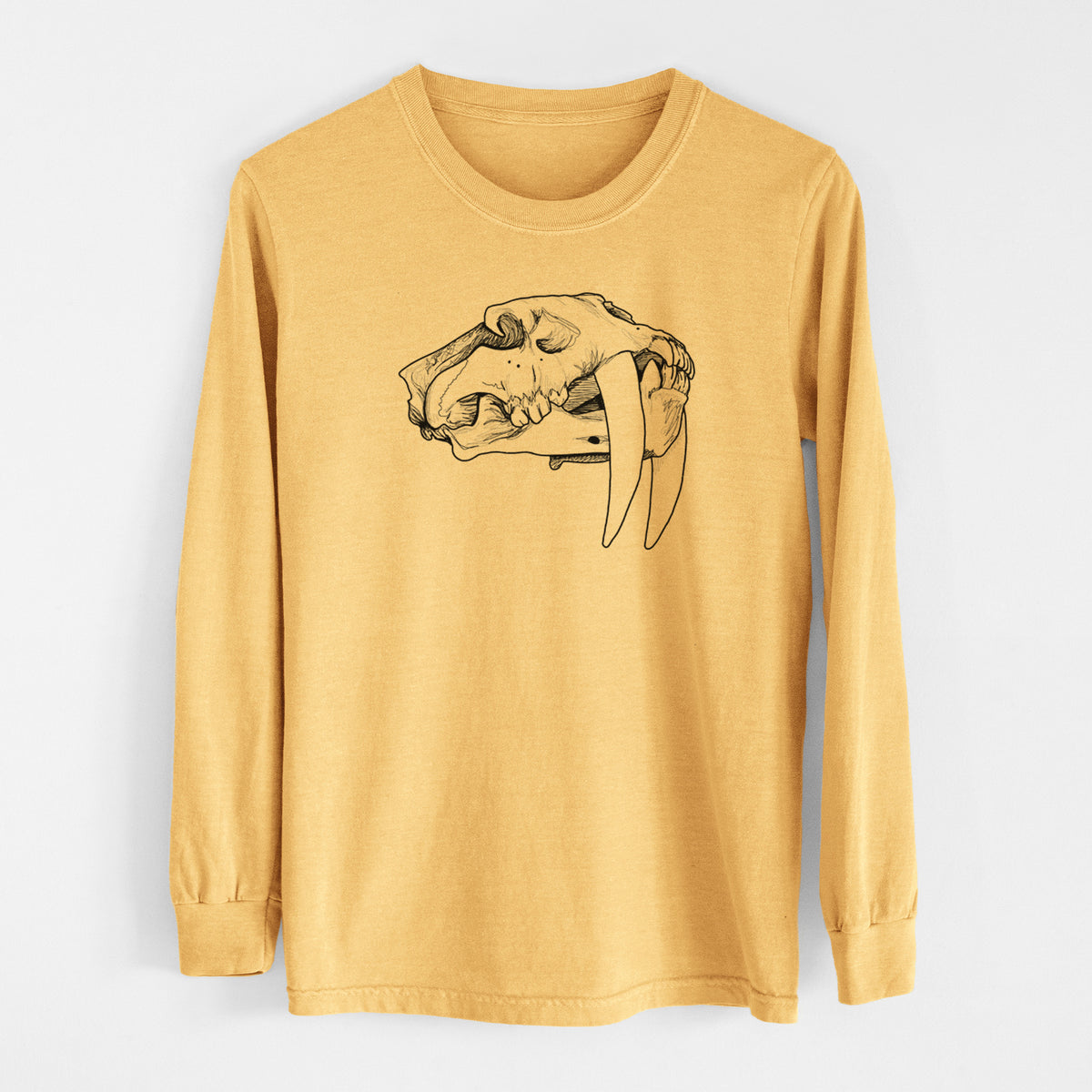 Golden wheat yellow Comfort Colors long sleeve shirt laid flat, printed with a detailed black ink illustration of a saber-toothed tiger skull.