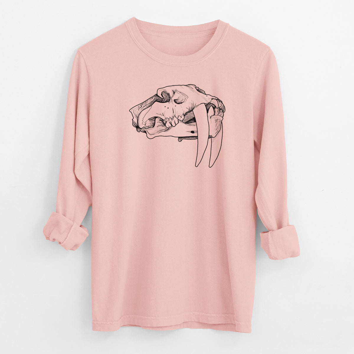 Peachy Comfort Colors long sleeve shirt laid flat with the cuffs rolled, printed with a detailed black ink illustration of a saber-toothed tiger skull.